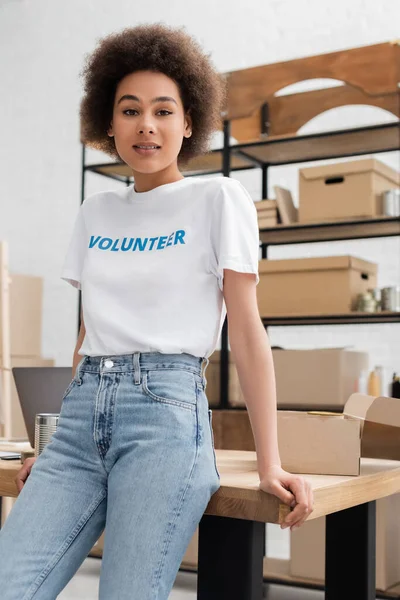 Joven afroamericana mujer de pie en el lugar de trabajo en el centro de voluntarios y mirando a la cámara - foto de stock