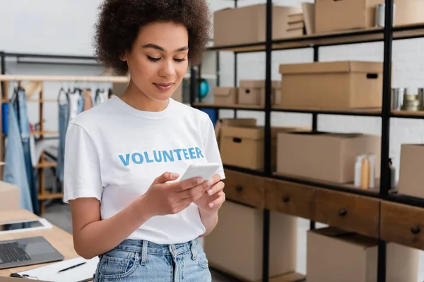 Junge afrikanisch-amerikanische Freiwillige mit Handy in Spendenzentrum — Stockfoto