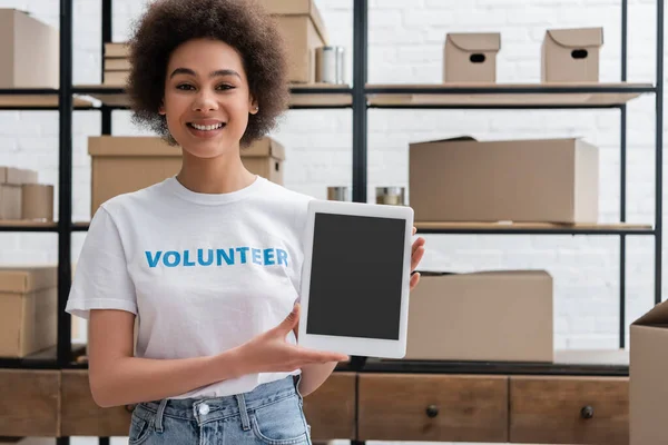 Feliz africano americano voluntario mostrando tableta digital con pantalla en blanco - foto de stock