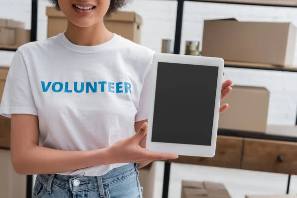 Visão parcial do sorridente voluntário afro-americano segurando tablet digital com tela em branco no centro de caridade — Fotografia de Stock