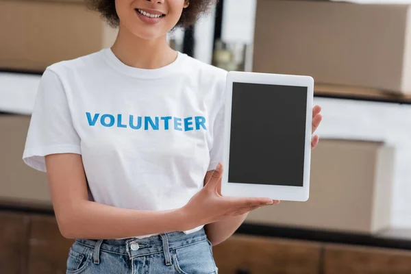 Vue recadrée d'un bénévole afro-américain tenant une tablette numérique avec écran vierge dans un centre de don — Photo de stock