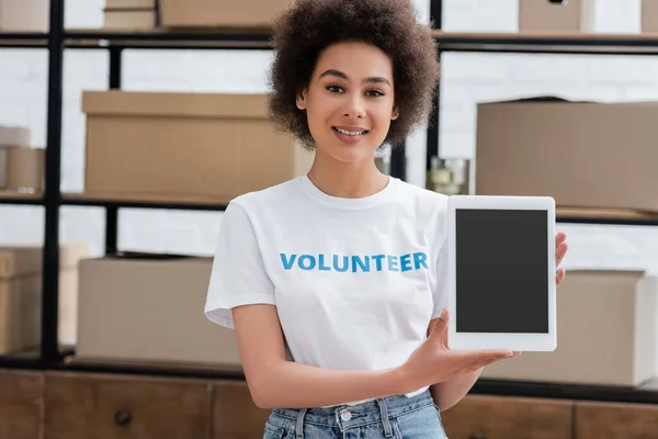 Щасливий афроамериканський волонтер тримає цифровий планшет з порожнім екраном у благодійному центрі — стокове фото