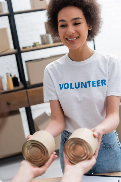 Young african american woman handing out humanitarian aid in volunteer center — Stock Photo