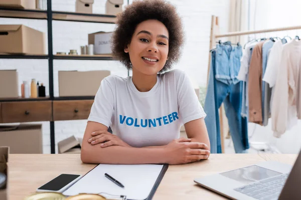 Happy african american volunteer sitting at workplace in charity center — Fotografia de Stock