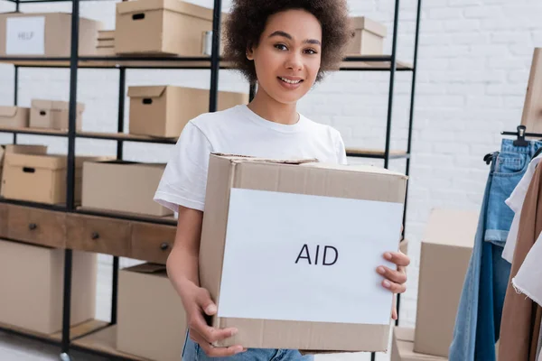 Усміхнений афроамериканський волонтер тримає коробку з написом у благодійному центрі — стокове фото
