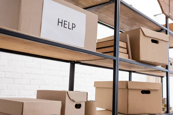 Caja de cartón con letras de ayuda en el estante en el almacén de caridad — Stock Photo