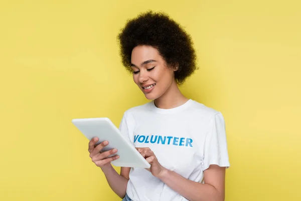 Gioioso volontario afroamericano utilizzando tablet digitale isolato su giallo — Foto stock