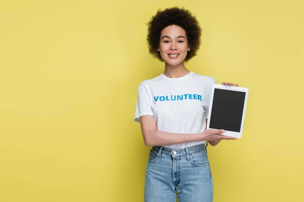 Pretty african american volunteer showing digital tablet with blank screen isolated on yellow — Photo de stock