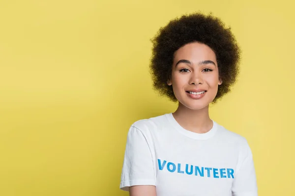 Young african american woman in t-shirt with volunteer inscription isolated on yellow — Foto stock