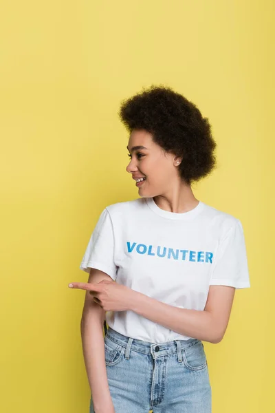 Joyful african american volunteer pointing away with finger isolated on yellow — Foto stock