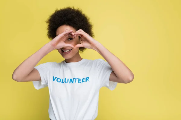 Feliz mulher afro-americana mostrando sinal de amor perto do rosto isolado no amarelo — Fotografia de Stock