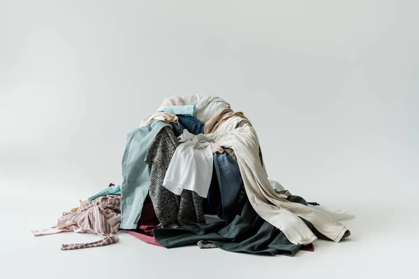 Pilha de várias peças de vestuário sobre fundo cinza — Fotografia de Stock