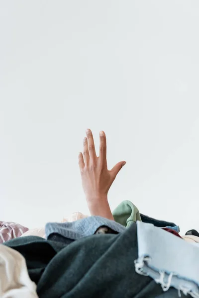 Vista recortada de la mano de mujer afroamericana cerca de pila de prendas de vestir sobre fondo gris - foto de stock