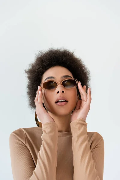 Lockige Afroamerikanerin passt trendige Sonnenbrille isoliert auf grau an — Stockfoto