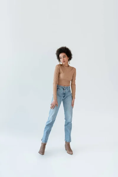 Full length of african american woman in jeans and cowboy boots on grey background — Fotografia de Stock