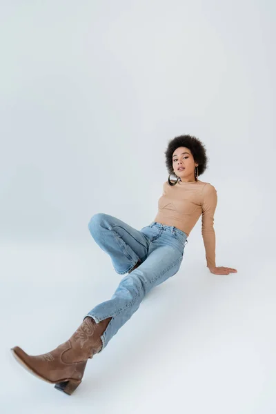 Comprimento total da mulher americana africana em jeans e camisa de manga comprida em fundo cinza — Fotografia de Stock