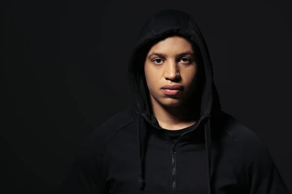 African american hooligan in hoodie looking at camera isolated on black — Photo de stock