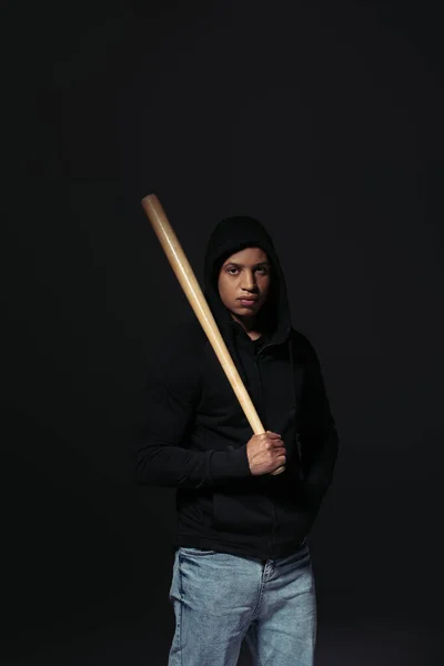 Hooligan afro-américain tenant batte de baseball et regardant la caméra isolée sur noir — Photo de stock