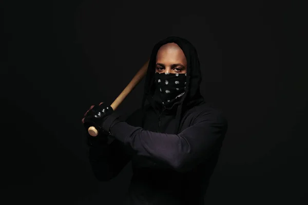 African american hooligan with mask on face holding baseball bat isolated on black — Foto stock