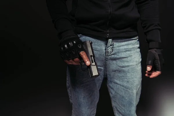 Cropped view of african american hooligan holding gun on black background — Stockfoto