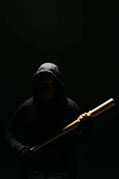 Silhouette of bandit in hoodie holding baseball bat isolated on black — Stock Photo