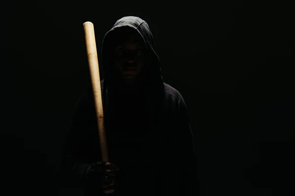 Silhouette of hooligan in hoodie holding baseball bat isolated on black with lighting — Stockfoto