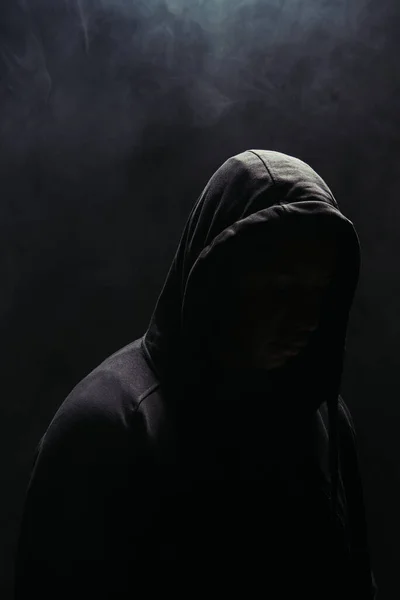 Silhouette of bandit in hoodie on black background with smoke — Foto stock