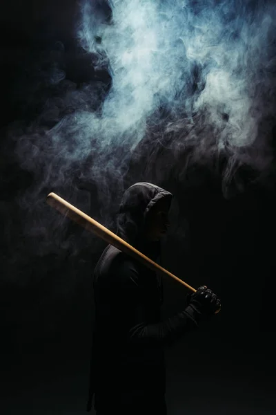 Silhouette of bandit with wooden baseball bat on black background with smoke - foto de stock