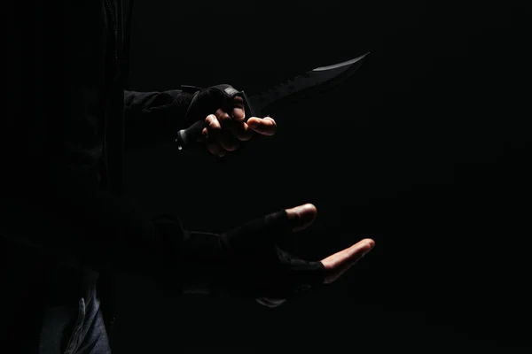 Vista recortada de bandido afroamericano en guantes con cuchillo aislado en negro - foto de stock