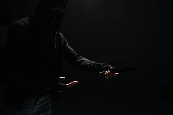 Silhouette of african american robber holding knife isolated on black - foto de stock