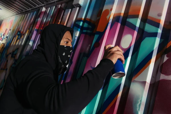 Vista lateral del graffiti de dibujo vándalo afroamericano en la pared - foto de stock
