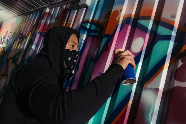 Side view of african american vandal drawing graffiti on wall — Foto stock