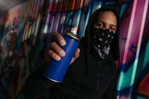 Blurred african american vandal holding spray paint near graffiti on wall — Stock Photo