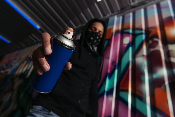 Low angle view of blurred african american vandal holding spray paint near graffiti on wall — Fotografia de Stock