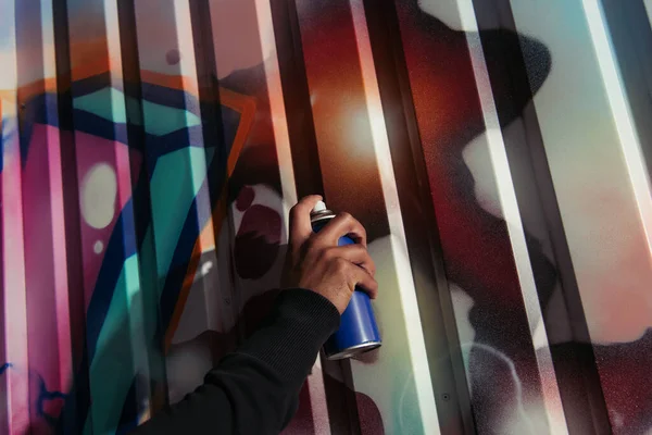 Cropped view of african american vandal drawing graffiti on wall on urban street - foto de stock