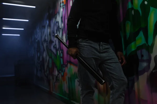 Cropped view of african american bandit holding baseball bat near graffiti on wall in garage — Stock Photo