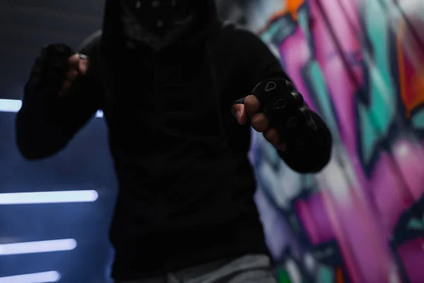 Cropped view of african american hooligan in gloves standing in fighting pose in garage — Stock Photo