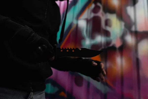 Cropped view of african american robber holding knife near graffiti on urban street — Stockfoto