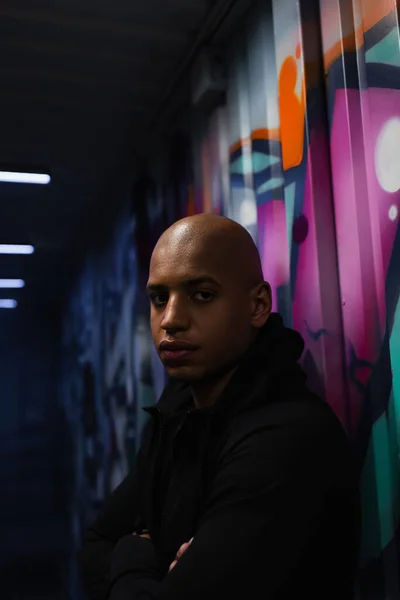 African american bandit crossing arms near graffiti on wall in garage — Stock Photo