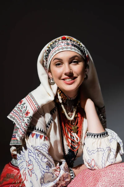 Portrait of happy young ukrainian woman in traditional clothing with ornament and red beads on black — Photo de stock