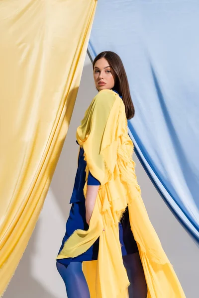 Bonita jovem mulher ucraniana em cor vestido bloco posando perto de cortinas azuis e amarelas — Fotografia de Stock