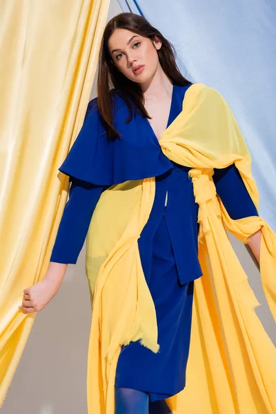 Trendy young ukrainian woman in color block dress posing near blue and yellow curtains — Foto stock