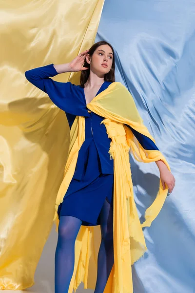 Brunette young ukrainian woman in color block clothes posing near blue and yellow curtains — Foto stock