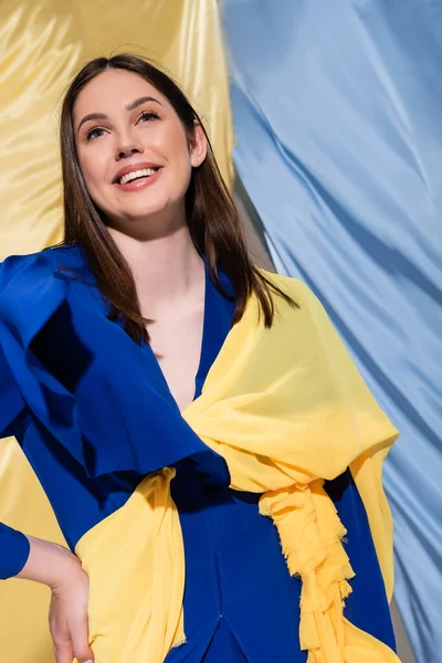 Positive ukrainian woman in color block clothing posing near blue and yellow flag — Foto stock