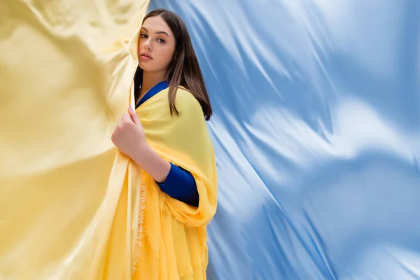 Patriotic ukrainian young woman with blue eyes posing near blue and yellow fabric — Stock Photo