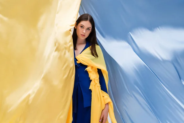 Morena ucraniano jovem mulher na moda roupas posando perto azul e amarelo bandeira — Fotografia de Stock