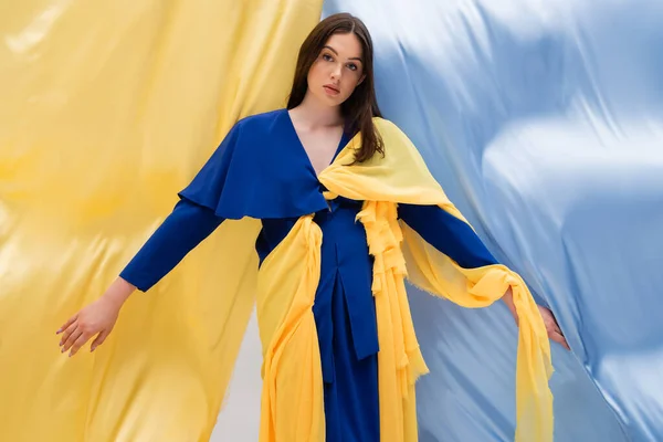 Modello ucraino patriottico in abito alla moda in posa vicino drappeggio blu e giallo — Foto stock