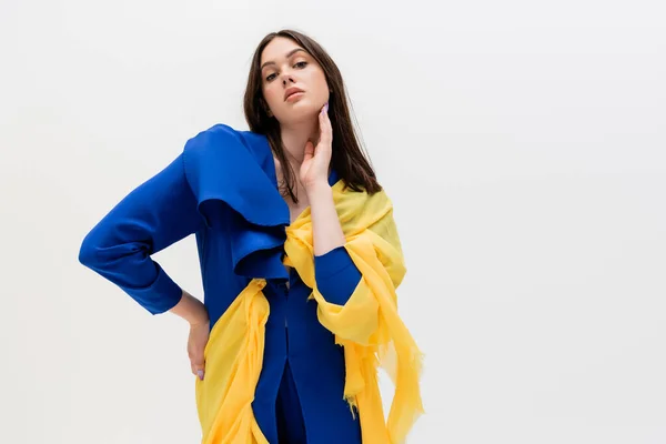 Confident ukrainian woman in blue and yellow outfit posing with hand on hip isolated on grey — Stock Photo