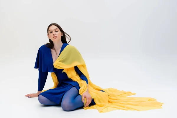 Confident anf patriotic ukrainian young woman in blue and yellow outfit posing on grey — Fotografia de Stock