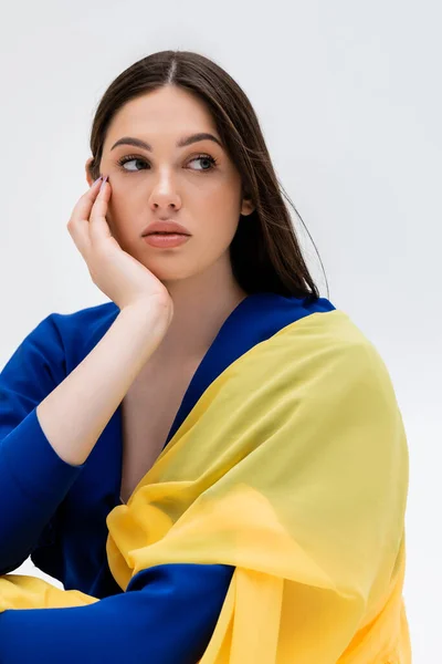 Dreamy ukrainian young woman in blue and yellow outfit looking away isolated on grey — Photo de stock